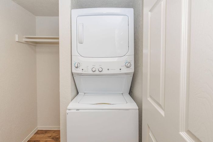 Efficient in-unit laundry with a modern stacked washer and dryer in a compact apartment setup.