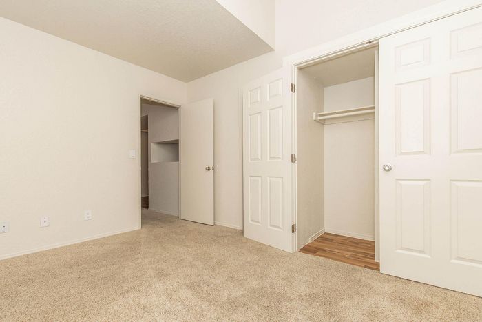 Inviting bedroom with plush carpet, spacious closet, and modern neutral tones perfect for personalization.