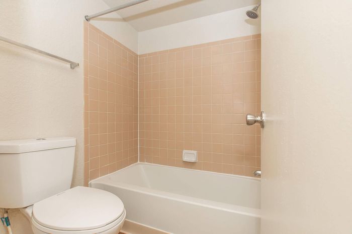 Charming bathroom with warm peach tiles, pristine white fixtures, and an inviting soaking tub.