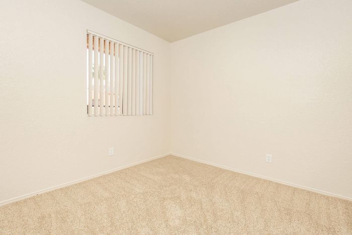 Bright and cozy room with plush carpet and large window, perfect for personalization and comfort.