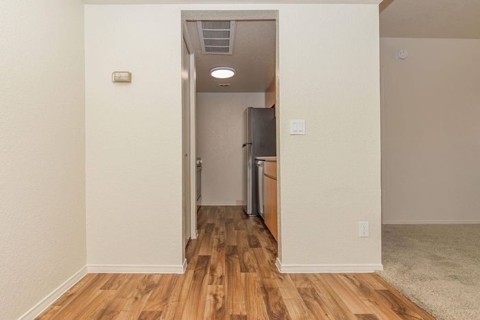 Bright entrance to a modern kitchen with sleek stainless steel appliances and elegant wooden flooring.