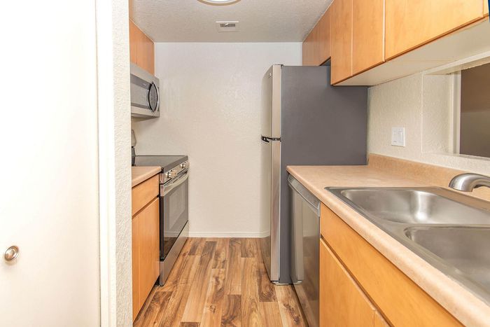 Modern kitchen with stainless steel appliances, sleek wooden cabinetry, and polished countertops on elegant wood flooring.