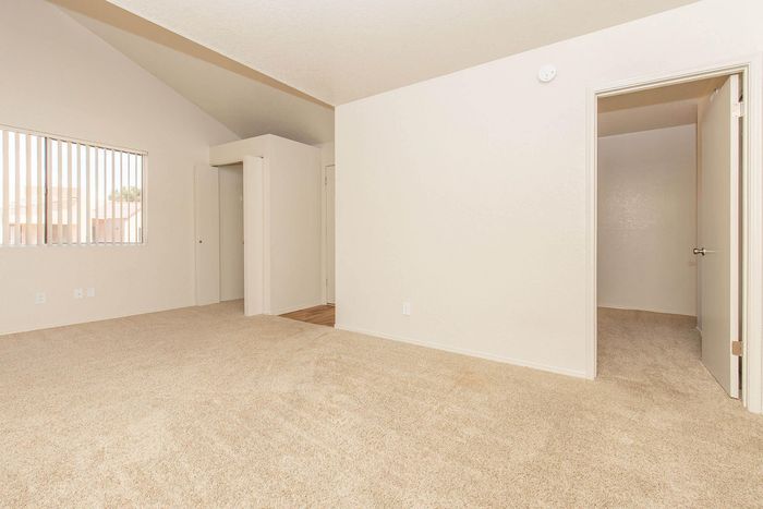 Inviting neutral-toned room with plush carpet and abundant natural light from large window.