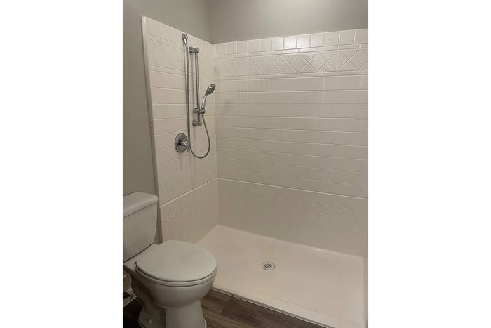 Modern bathroom featuring a sleek walk-in shower with contemporary fixtures and pristine white tiles.