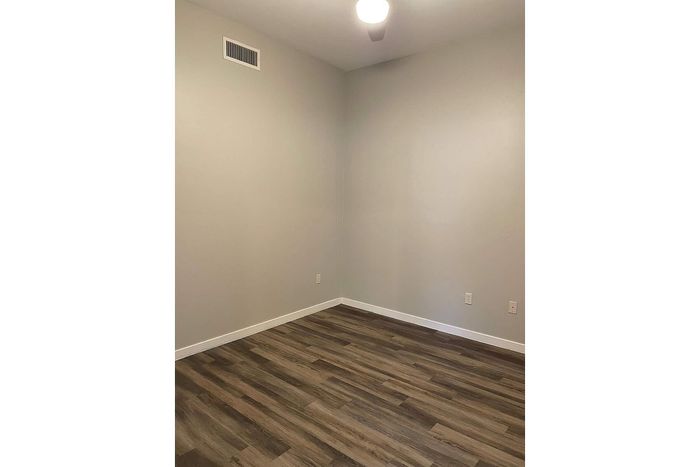 Bright and modern room with sleek hardwood flooring and soft neutral walls, perfect for customization.