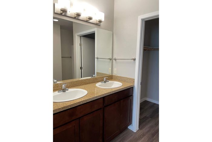 Modern apartment bathroom featuring elegant double sinks with stylish vanity lighting and classic wood cabinetry.