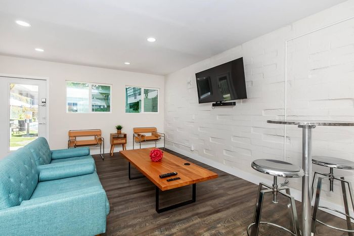 Contemporary living room featuring a stylish blue sofa, chic wooden coffee table, and wall-mounted TV, with modern decor and ample natural light.