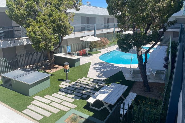 Inviting courtyard featuring a sparkling pool and lush greenery, complemented by modern grilling stations and shaded picnic areas.