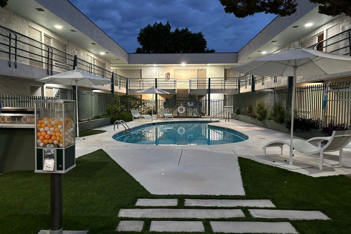 Charming courtyard view featuring a serene swimming pool surrounded by stylish loungers and umbrellas, ideal for relaxation and leisure.