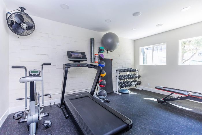 Bright and modern home gym featuring a treadmill, exercise bike, free weights, and workout equipment, perfect for fitness enthusiasts.
