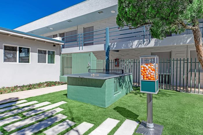 Charming apartment courtyard featuring a ping pong table, lush greenery, and vibrant outdoor ambiance.