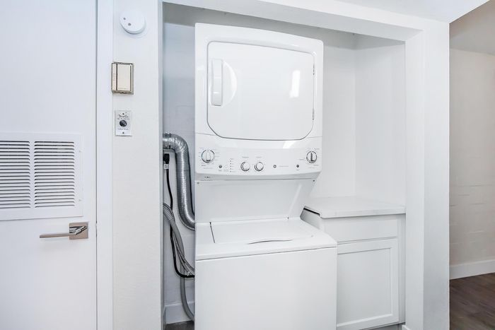 Modern apartment laundry area featuring a sleek stackable washer and dryer unit within a bright and spacious utility closet.