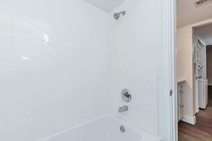 Sleek and modern bathroom featuring a pristine bathtub with chrome fixtures, offering a relaxing retreat.