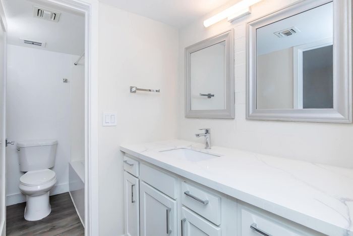 Sleek and modern bathroom with elegant marble countertop, ample cabinetry, and exquisite lighting, perfect for comfort and style.