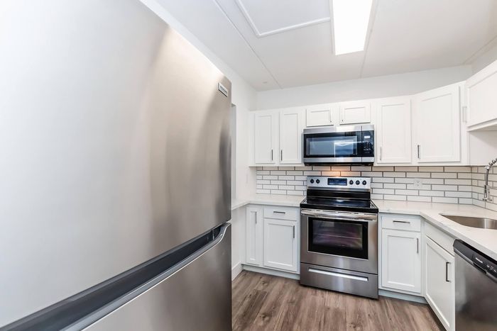 Modern kitchen with sleek stainless steel appliances, white cabinetry, and elegant subway tile backsplash.