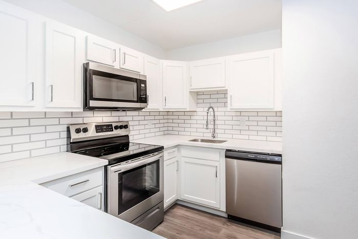 Modern kitchen with sleek stainless steel appliances, elegant white cabinetry, and a stylish subway tile backsplash, creating a fresh and inviting atmosphere.