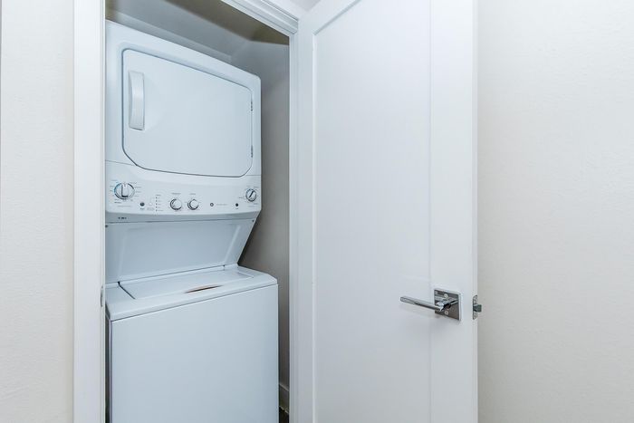 Compact utility space featuring a sleek, modern stackable washer and dryer enclosed by a stylish white door.