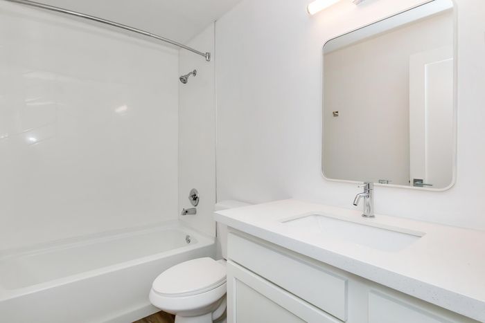 Bright and modern bathroom with a sleek vanity, stylish mirror, and shower-bathtub combo, offering a clean and elegant space.