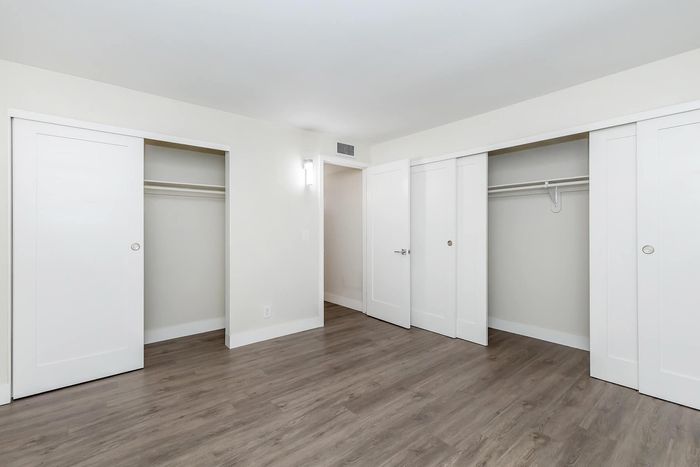 Bright, spacious room with elegant wood flooring and multiple closets ideal for stylish storage.