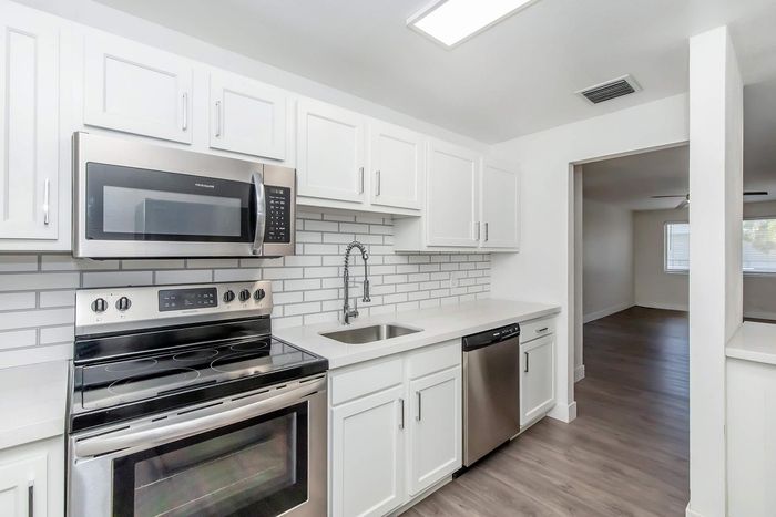 Modern kitchen with stainless steel appliances, sleek white cabinetry, and spacious countertops in a bright, contemporary apartment.