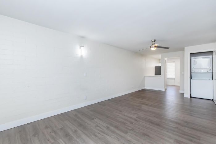 Bright and spacious apartment with sleek wood flooring, modern ceiling fan, and in-unit laundry facilities.