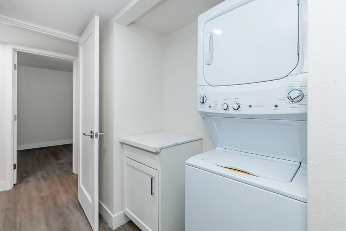 Modern apartment laundry area with an efficient stacked washer and dryer next to ample storage space.