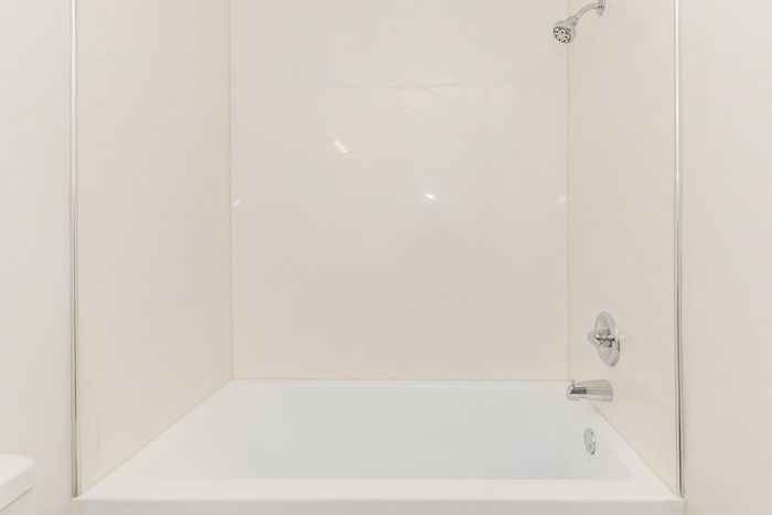 Pristine white bathtub in a spa-like bathroom setting, offering a serene and relaxing bathing experience.