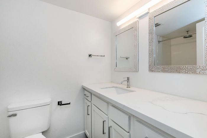 Elegant bathroom featuring a sleek white vanity with modern fixtures and a stylish framed mirror.