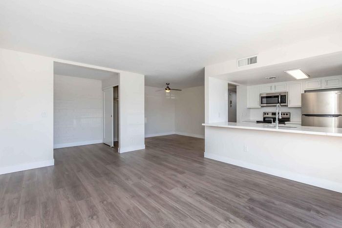 Sleek apartment interior showcasing an open-plan layout with modern stainless steel kitchen appliances and elegant hardwood flooring.