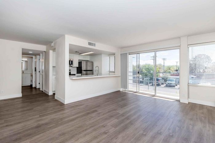 Bright and spacious open-plan living area with modern kitchen and large windows offering abundant natural light and balcony access.