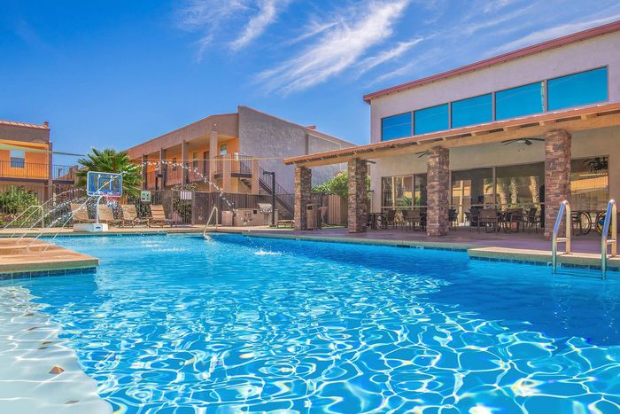 Inviting outdoor pool area with sparkling water, modern lounge chairs, and shaded patio for ultimate relaxation.