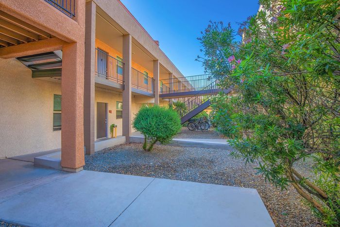 Inviting apartment exterior with lush greenery and modern architecture, featuring convenient bike storage and sunlit pathways.