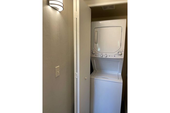 Modern apartment featuring a convenient in-unit stacked washer and dryer set, seamlessly integrated into a sleek storage space.
