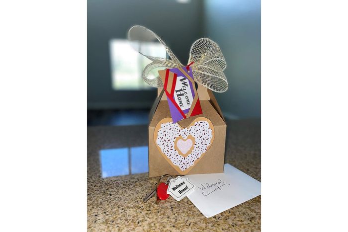 Charming welcome package with a decorative gift box, keys with a 'Welcome Home' tag, and a heartfelt card on a granite countertop.