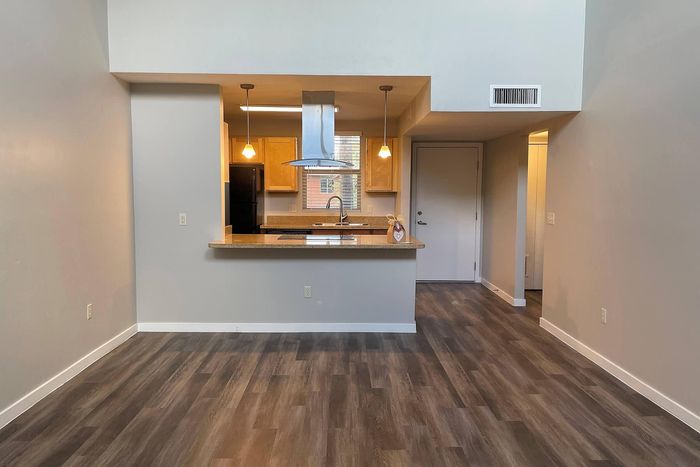 Chic open kitchen with modern lighting, sleek countertops, and inviting wood flooring, perfect for contemporary living.