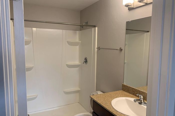 Modern bathroom featuring a sleek white shower, elegant vanity with granite countertop, and polished fixtures.