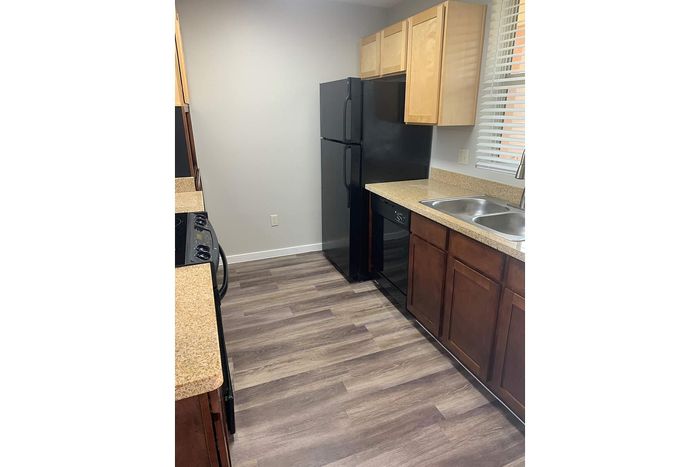 Modern kitchen with sleek dark appliances, wood cabinetry, and elegant countertops, creating a warm and inviting cooking space.
