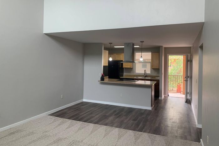 Modern open-concept apartment showcasing a stylish kitchen with pendant lighting, sleek countertops, and balcony access.