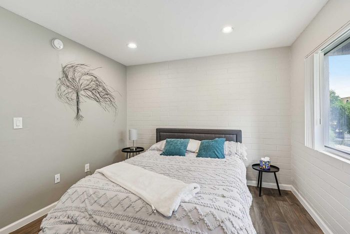 Chic bedroom with modern decor, featuring a cozy bed with textured bedding, stylish wall art, and ample natural light through a large window.