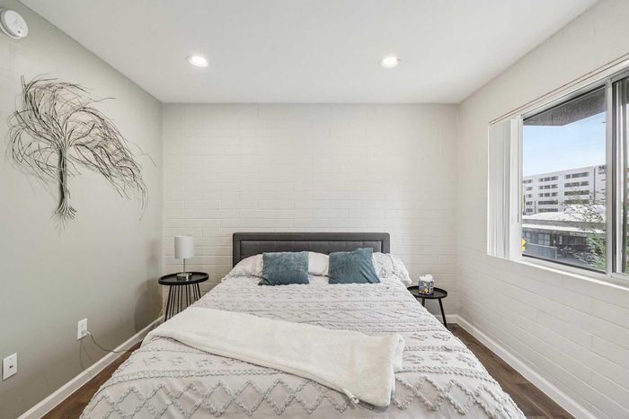 Cozy bedroom with elegant d&eacute;cor, natural light from large window, and stylish wall art, offering a serene retreat.