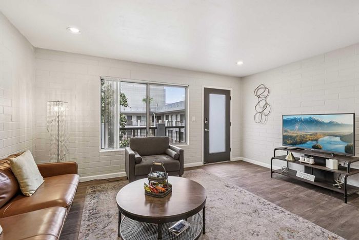 Chic living room with modern decor featuring a sleek leather sofa, flat-screen TV, and large window with natural light.