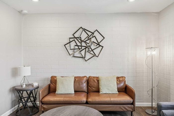 Elegant living room with a stylish brown leather sofa, modern geometric wall art, and a chic crystal floor lamp, creating a cozy and inviting atmosphere.