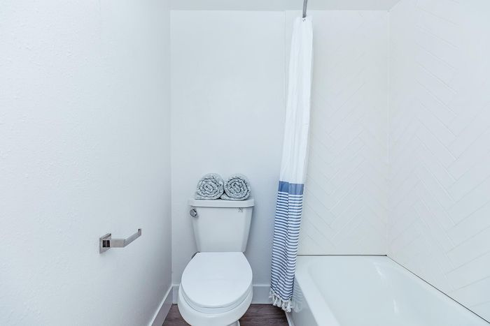 Modern bathroom featuring a sleek white toilet, elegant blue-striped shower curtain, and contemporary wall tile design.