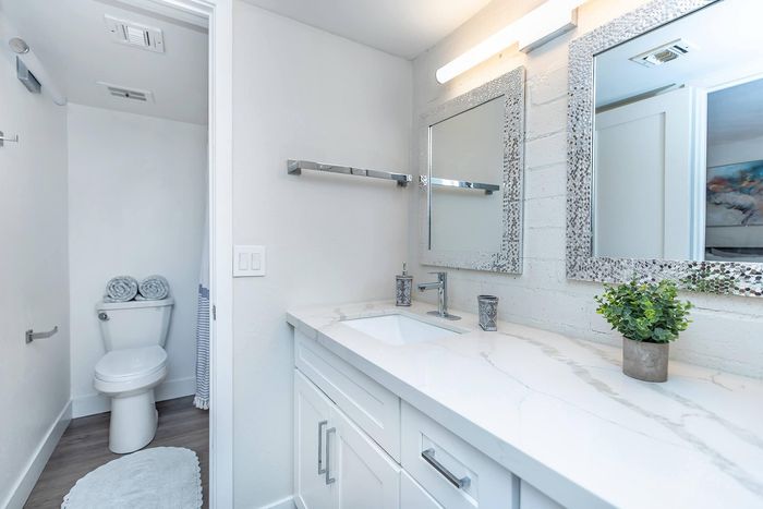 Bright and modern bathroom with elegant dual mirrors, sleek vanity, and stylish decor touches.