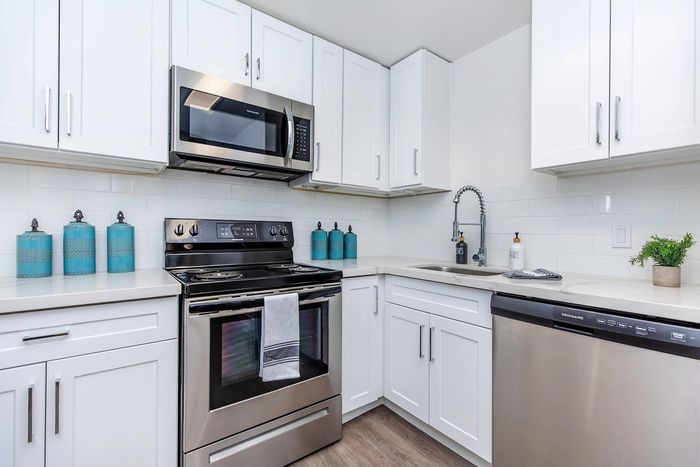 Sleek modern kitchen with white cabinetry, stainless steel appliances, and elegant turquoise accents.