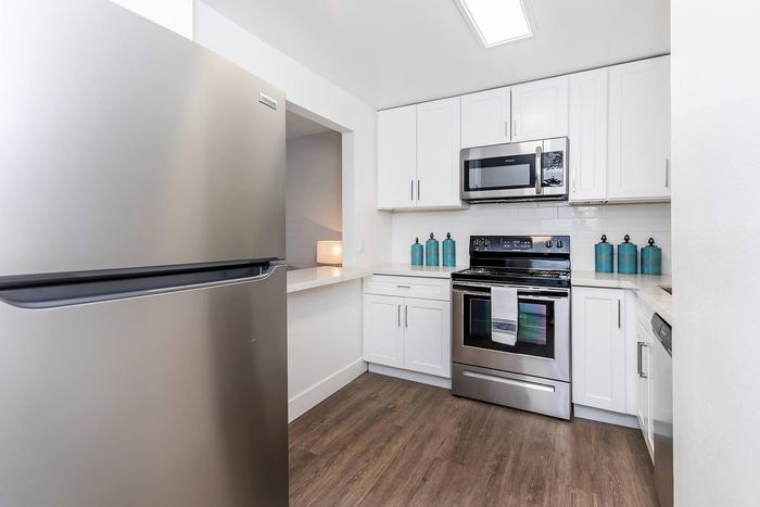 Modern kitchen featuring sleek stainless steel appliances, elegant white cabinetry, and stylish hardwood flooring.