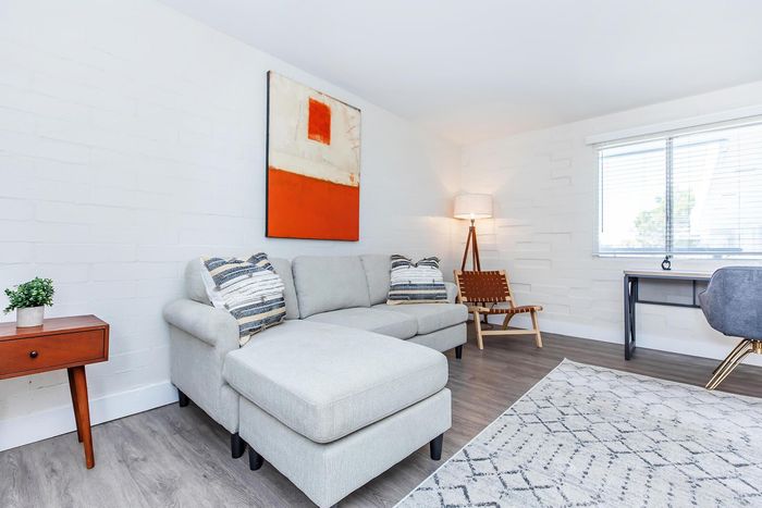 Modern living room with a cozy gray sectional sofa, abstract wall art, and a stylish wooden floor lamp, perfect for relaxation and entertaining.