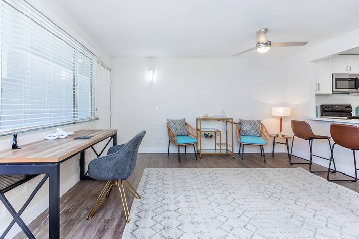 Bright and modern living space featuring stylish furnishings, a chic wooden desk, and an inviting kitchen breakfast bar.