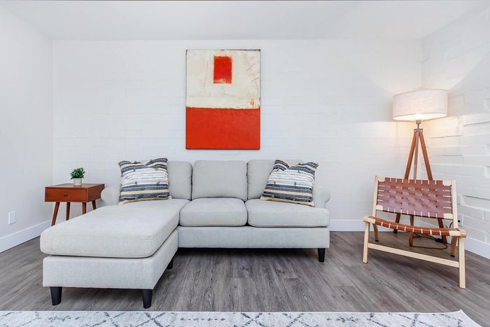 Bright living room featuring a modern gray sectional sofa, artistic wall decor, and elegant hardwood flooring, perfect for relaxation.
