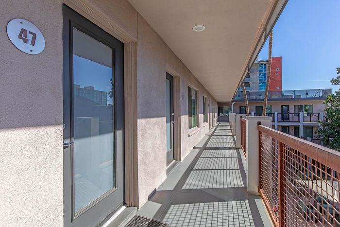 Bright apartment corridor with modern doors and sleek design, offering a view of the nearby urban landscape.